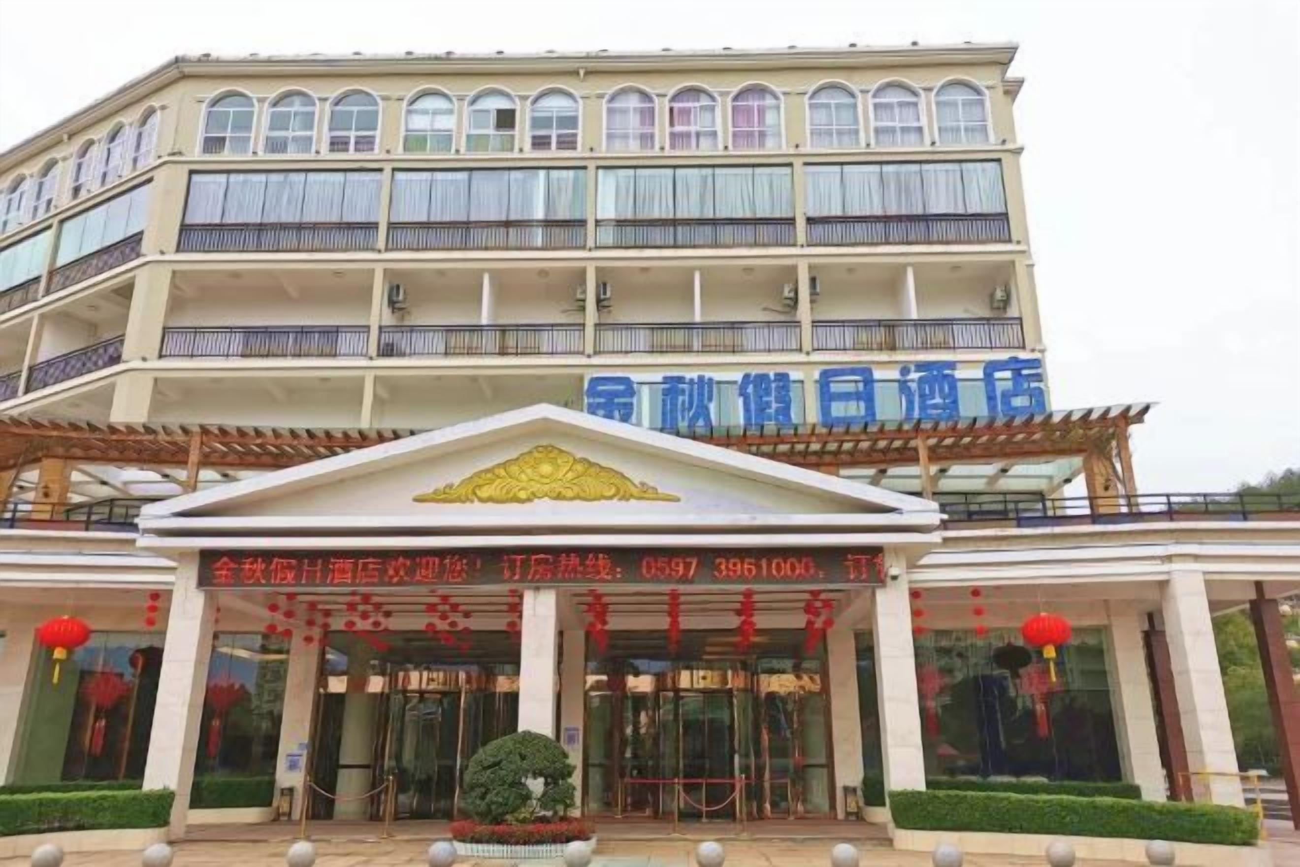 A multi-story hotel with a prominent entrance, a signboard with contact information, and a well-maintained exterior.