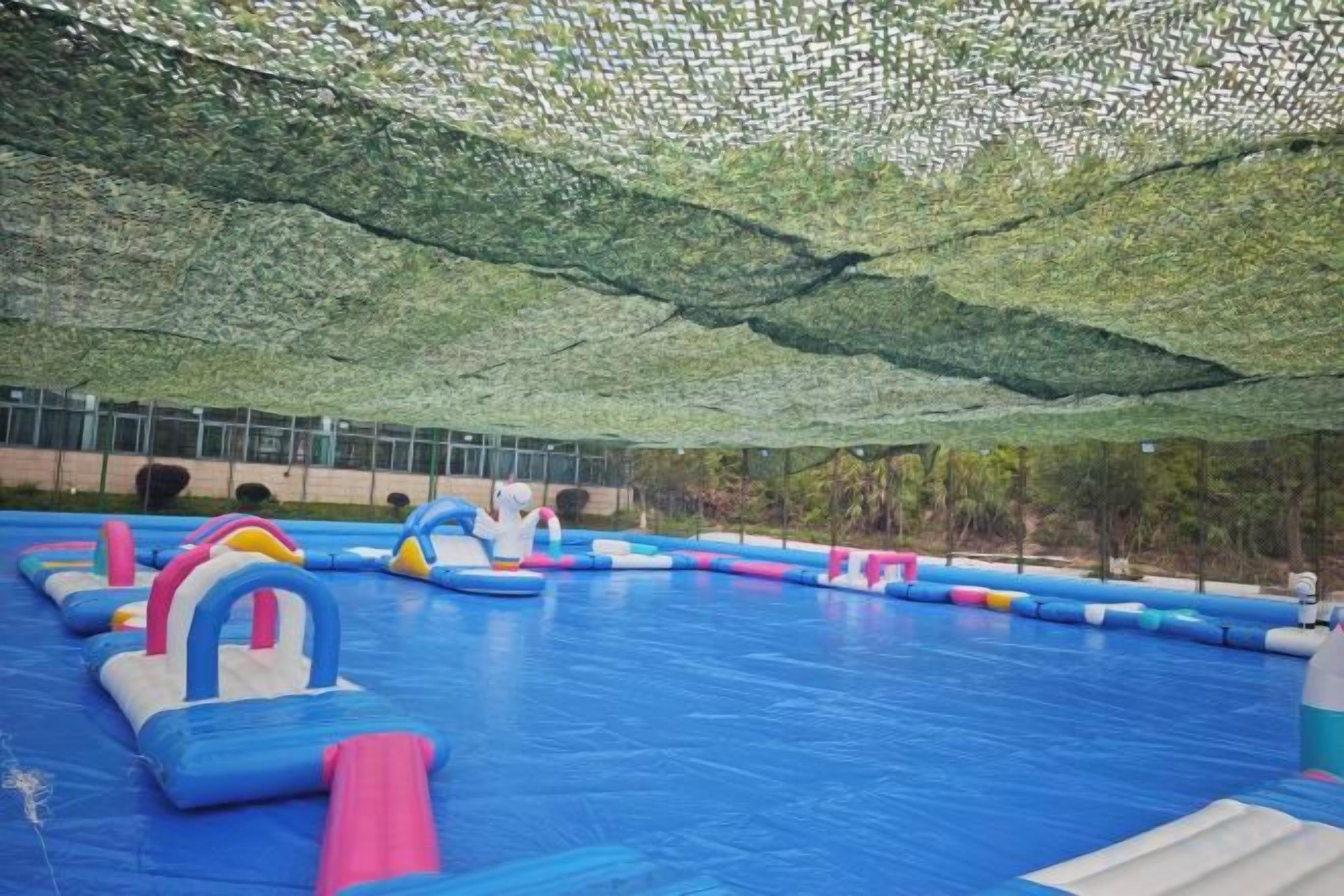 Zona de juegos interior con estructuras hinchables y techo cubierto con malla.