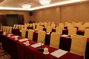 A conference room with rows of tables, each with a microphone, papers, and a red tablecloth. - Jinqiu Holiday Hotel (Shanghang)
