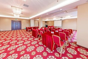A conference room with a red carpet, round tables, and chairs.