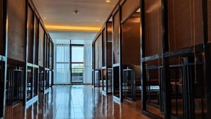 Un pasillo con puertas y ventanas de vidrio, que conduce a una habitación luminosa con vistas.