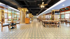Un restaurante espacioso con techos altos, mobiliario de madera y suelo estampado.