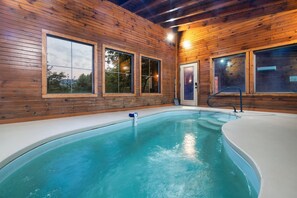 A wooden cabin with a swimming pool, large windows, and a door.