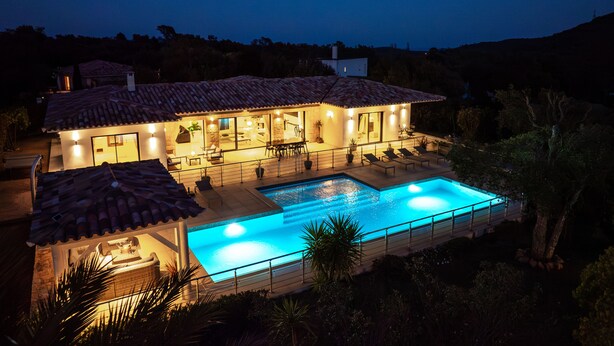 Et toetagers hus med swimmingpool, udendørs siddepladser og en godt oplyst patio.