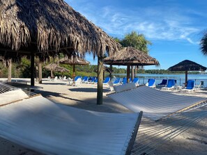 A beach with hammocks, lounge chairs, and thatched-roof structures.