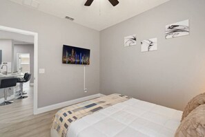 Ein Schlafzimmer mit einem Bett, einem Schreibtisch und Stühlen, sowie einem Stadtbild an der Wand.