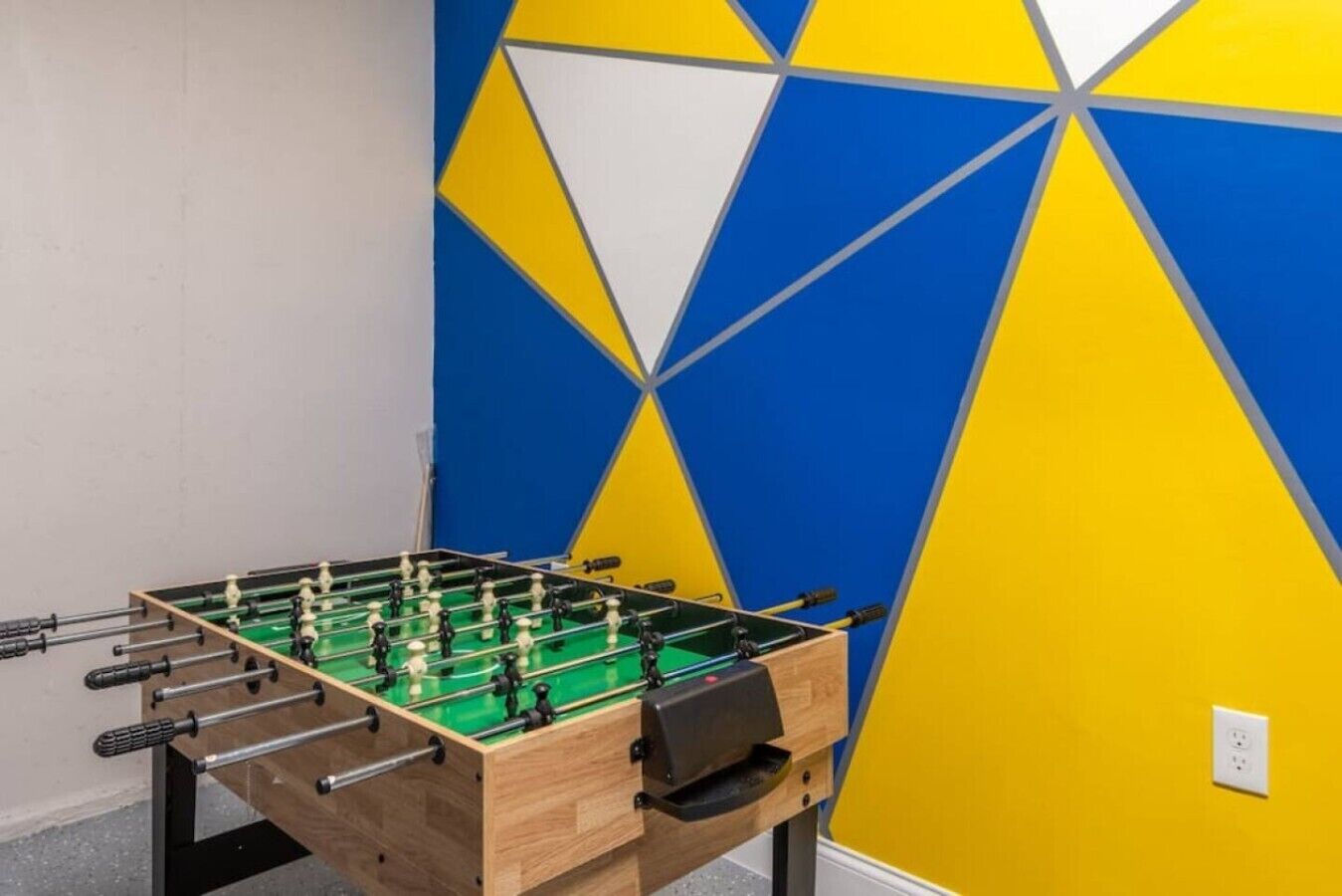 Una mesa de fútbol de mesa en una habitación con un diseño geométrico en la pared.