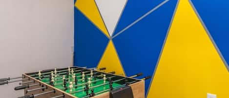 Une table de baby-foot dans une pièce dont le mur est décoré de motifs géométriques.