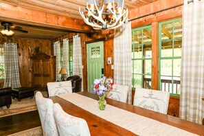 Un intérieur en bois comprenant une table à manger, des chaises, un lustre et des rideaux.