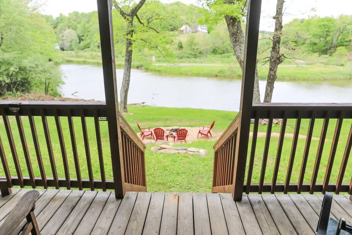 Terraza de madera con vistas a un lago y sillas.