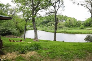 Une vue sur le lac, avec des arbres, une zone herbeuse et un bâtiment doté d’une terrasse.