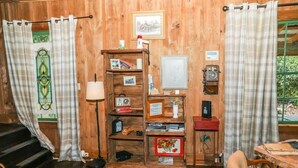 Une pièce aux murs lambrés, avec une bibliothèque en bois, un bureau, une chaise et un escalier.