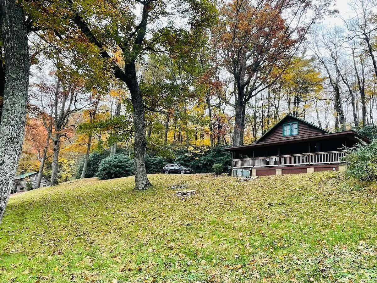 Eine Hütte mit Veranda, umgeben von Bäumen im Herbstlaub.