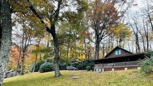 Une cabane dotée d’une véranda, entourée d’arbres aux feuilles d’automne.