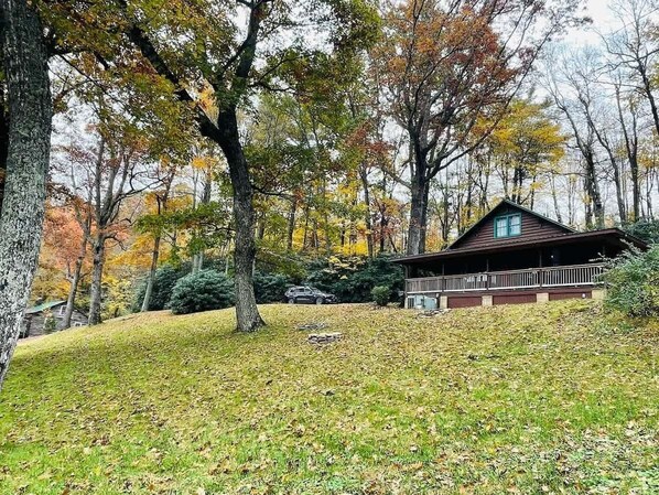 Eine Hütte mit Veranda, umgeben von Bäumen im Herbstlaub.