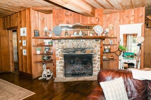 Une pièce chaleureuse avec une cheminée en pierre, des murs en bois et un canapé en cuir.