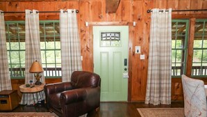 Un intérieur en bois avec une porte verte, un canapé en cuir et un tapis à motifs.