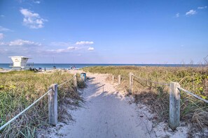 A sandy path leading to a lifeguard tower at a beach.