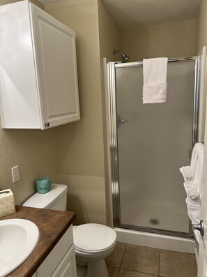 A bathroom with a toilet, sink, and shower stall. - Washburn Hotel Suites (Topeka)