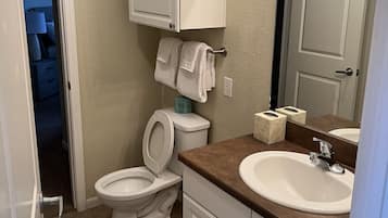 A bathroom with a toilet, sink, and cabinet.
