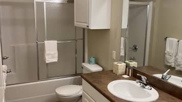 A bathroom with a shower, toilet, sink, and vanity.