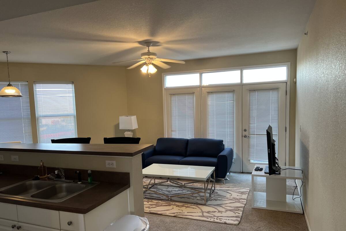A compact living space with a kitchenette, a ceiling fan, a sofa, a coffee table, and a TV.