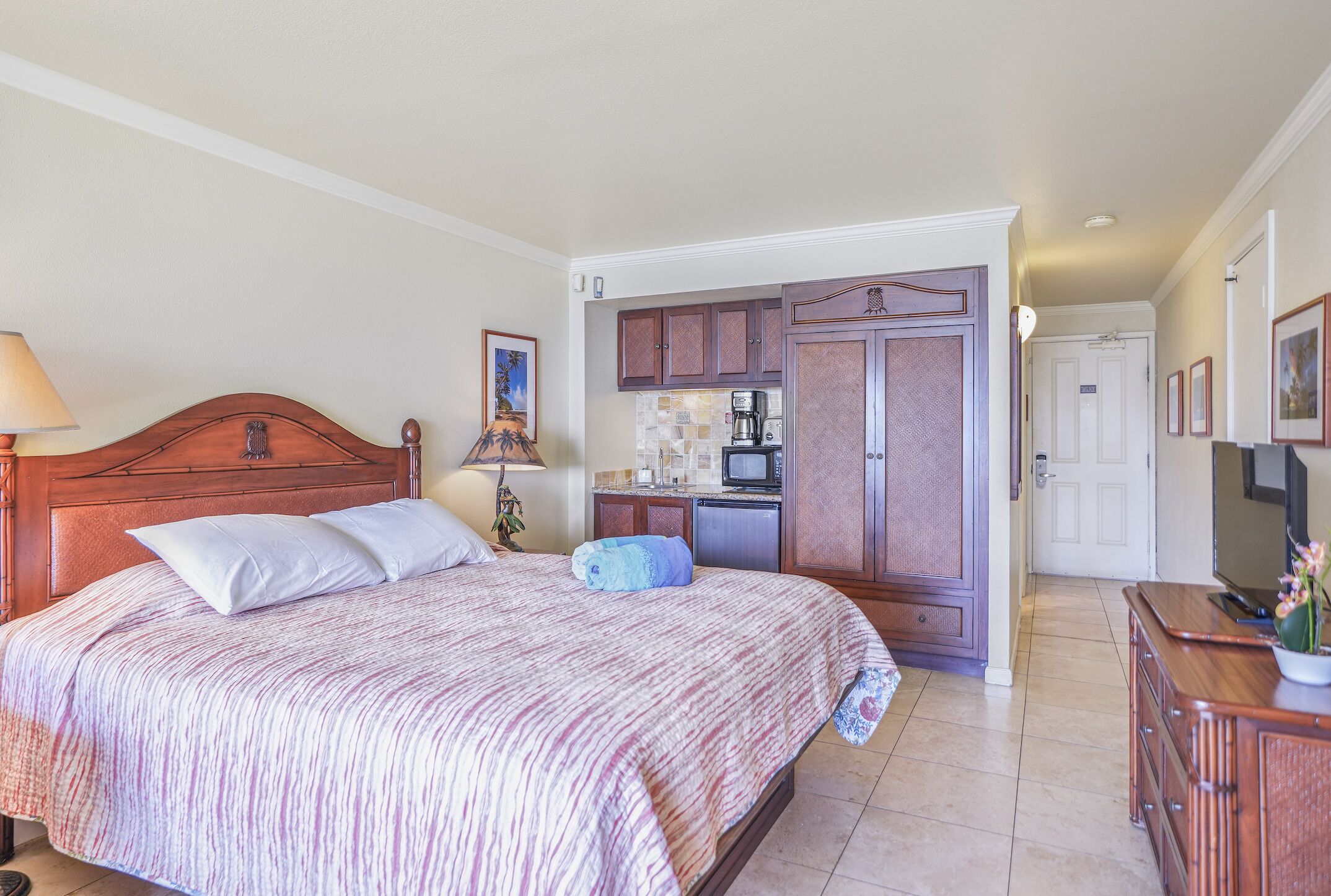 A bedroom with a large bed, a wooden headboard, a bedside table with a lamp, and a small decorative item.