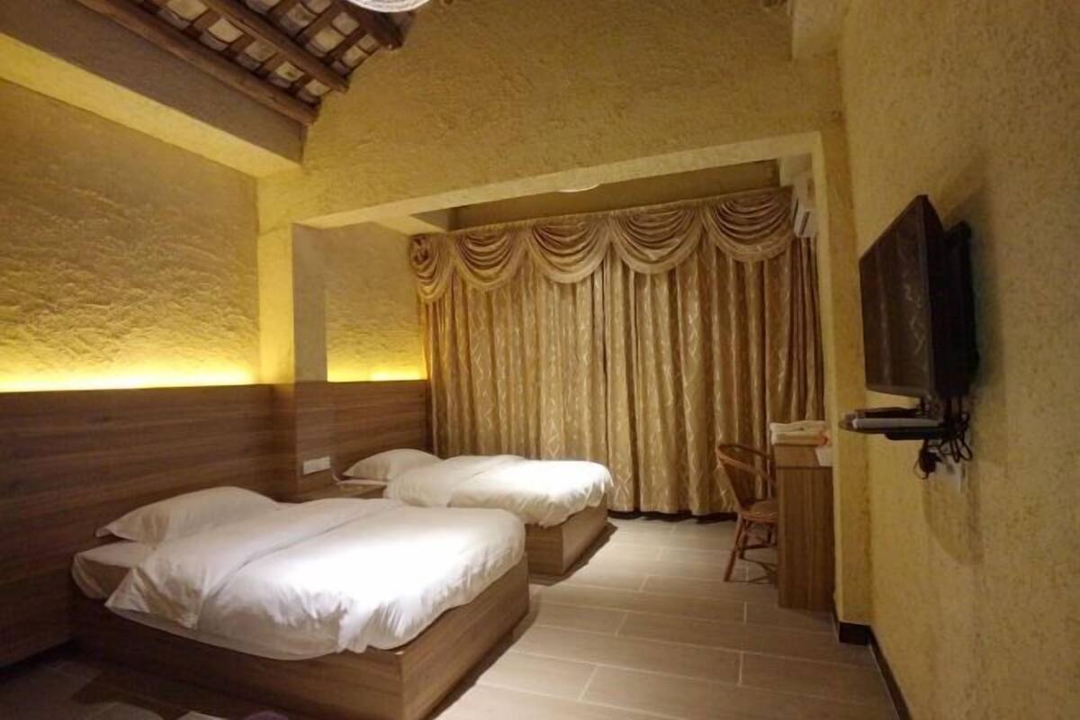 Une chambre avec deux lits, un bureau et une télévision.