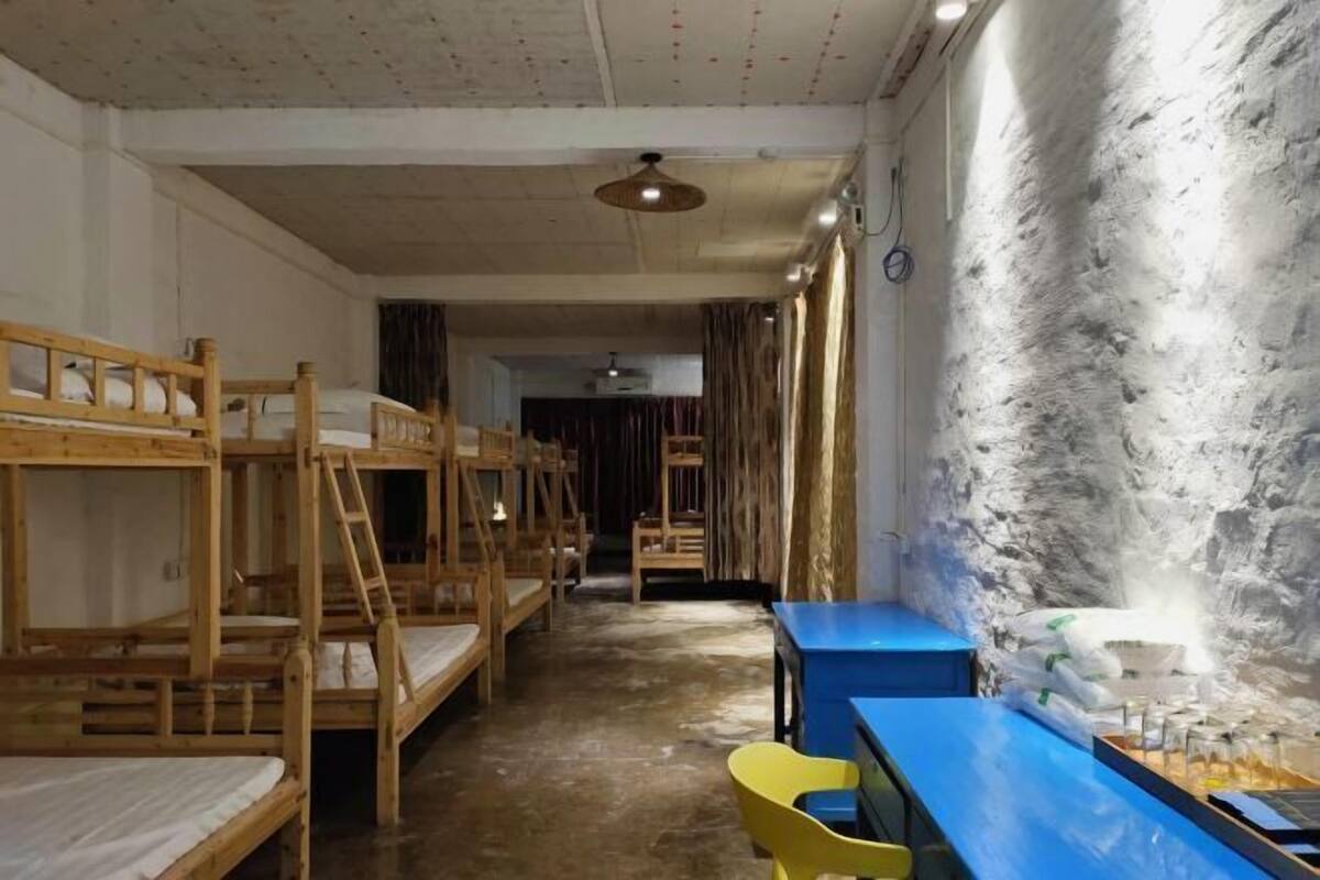 Une chambre de dortoir avec des lits superposés, un bureau, des chaises et un grand mur à texture.
