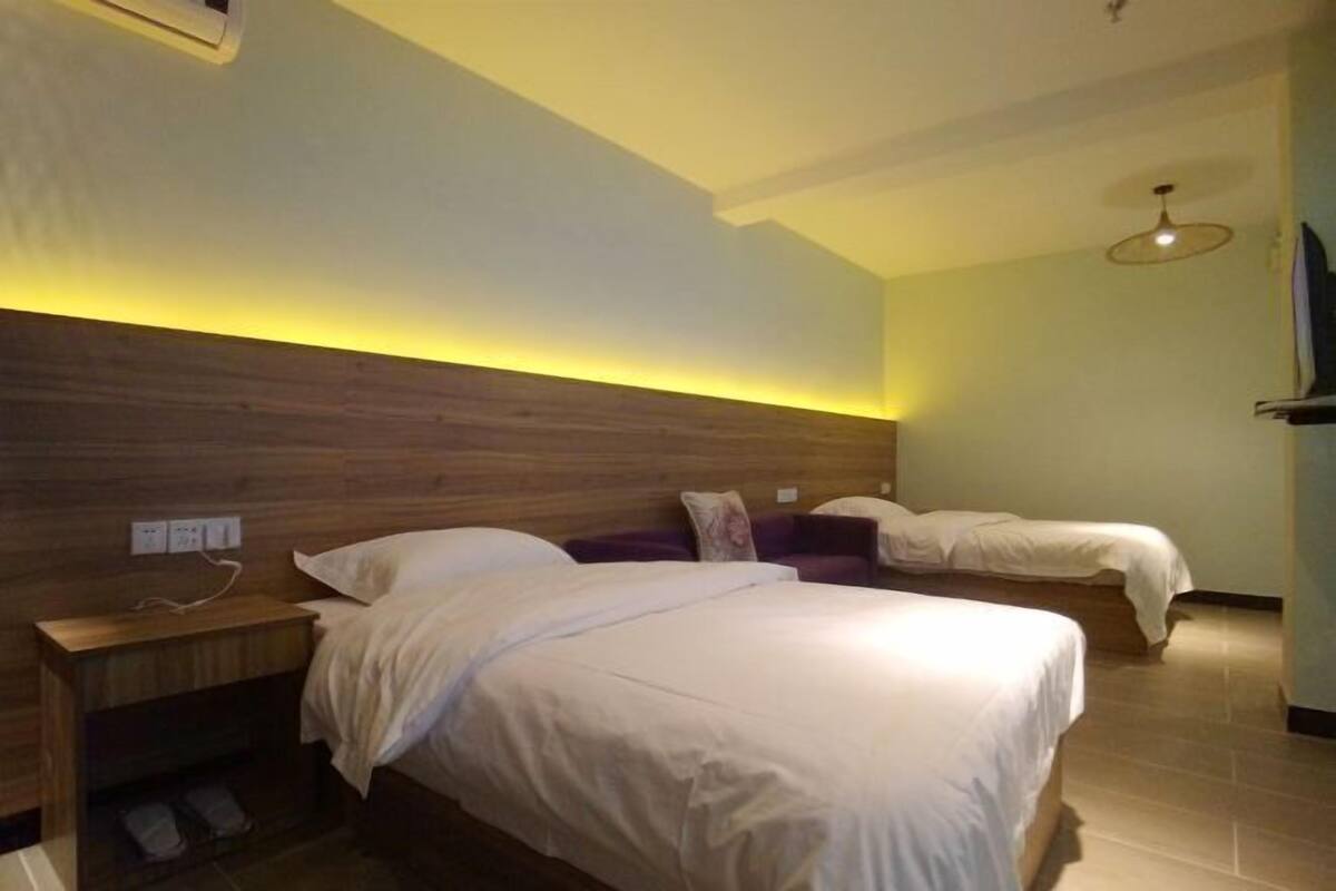 Une chambre d’hôtel avec une tête de lit en bois, deux lits, une table de chevet et un téléviseur.