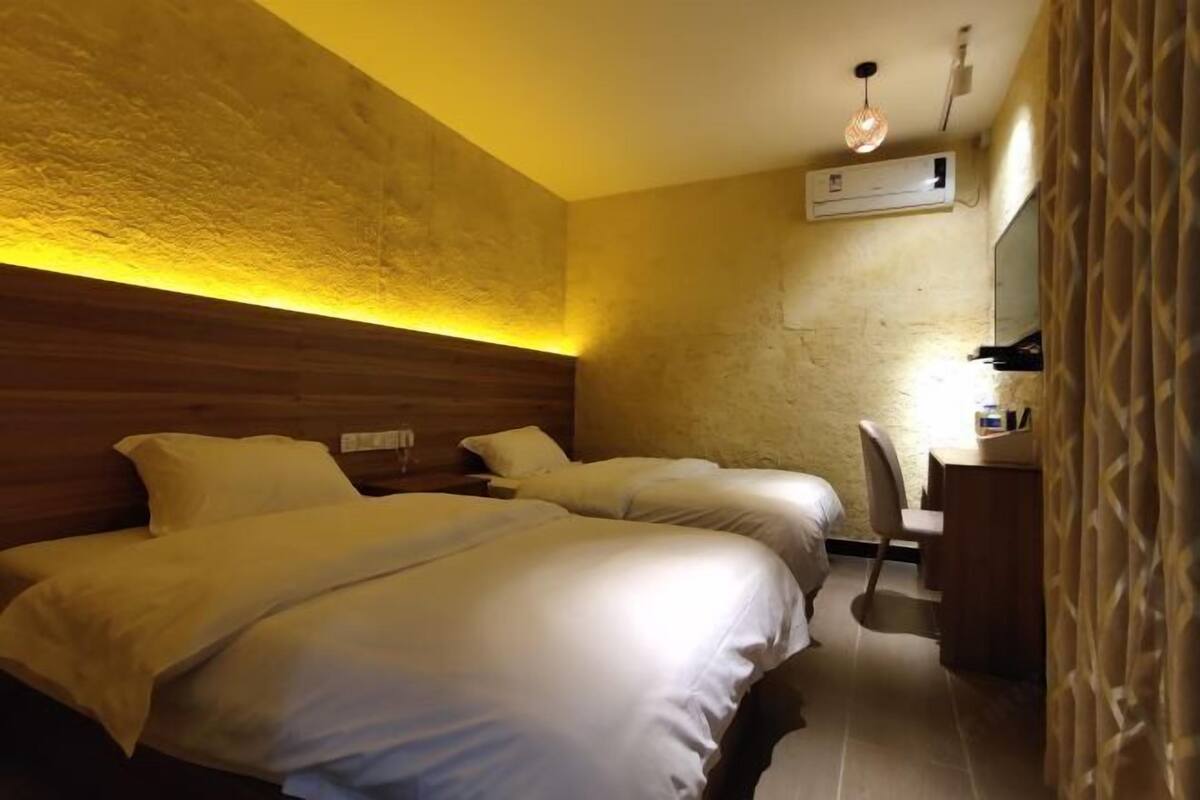 Une chambre d’hôtel avec deux lits, un bureau et une chaise.