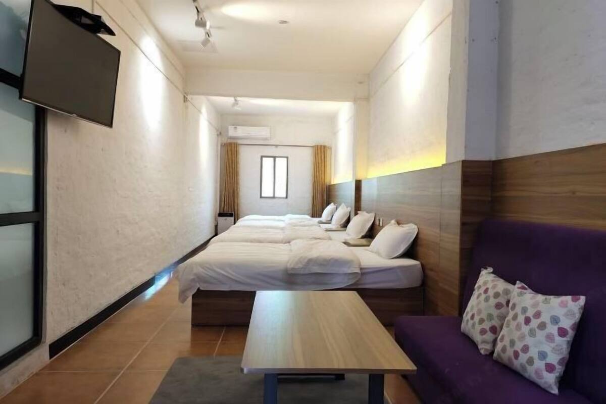 Une chambre d’hôtel avec un grand lit, un canapé, une télévision et une fenêtre.