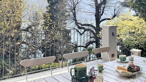 Una terrazza con un tavolo apparecchiato per mangiare, circondata da ringhiere metalliche e alberi.