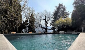Ein Schwimmbecken mit Blick auf Bäume und einen klaren Himmel.