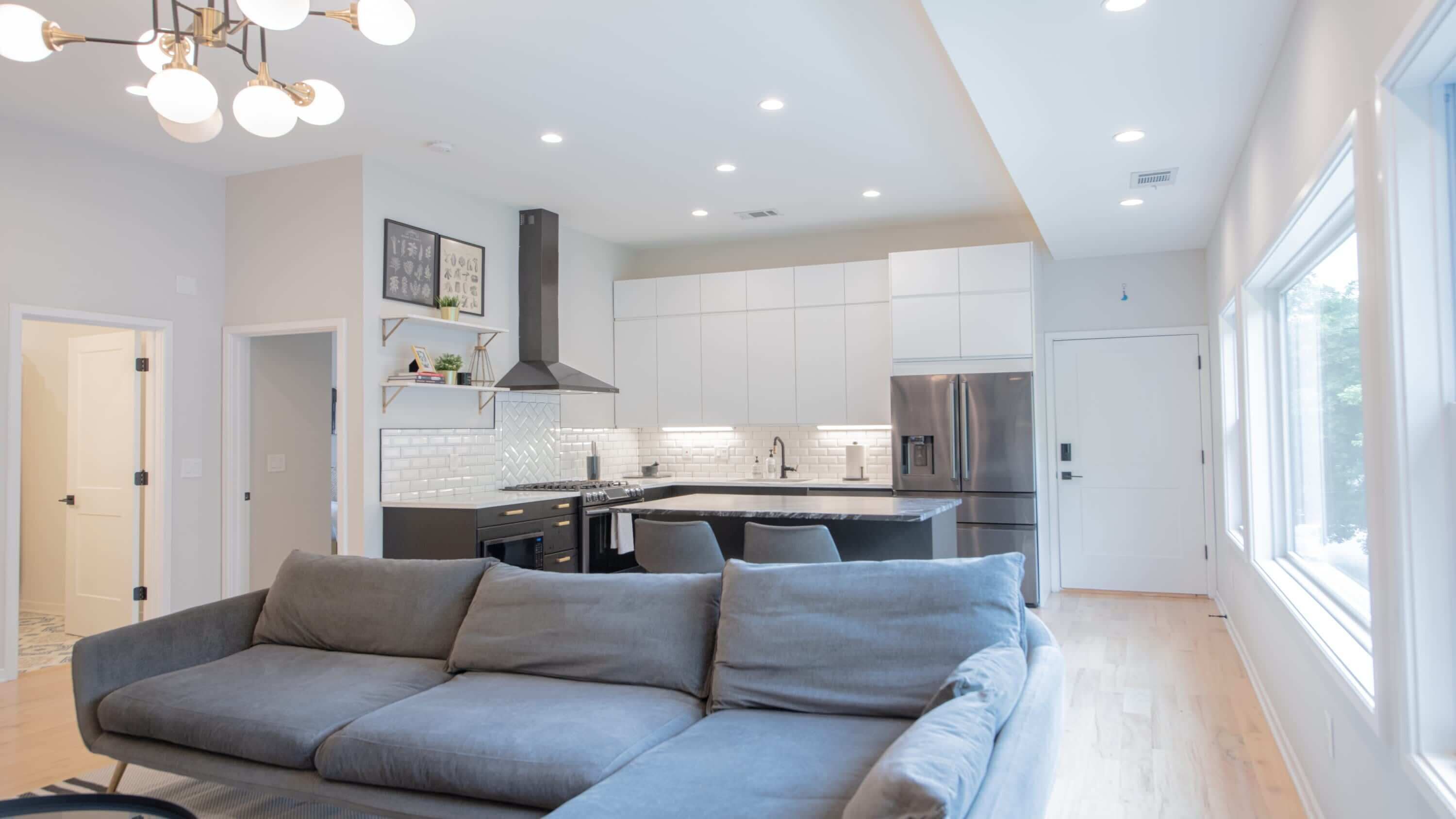 A modern kitchen with white cabinets, a stainless steel refrigerator, and a built-in island.