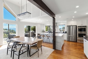 A modern kitchen with a large island, stainless steel appliances, and a view of the outdoors.