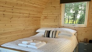 Un dormitorio con paneles de madera, una cama, almohadas y una mesita de noche.