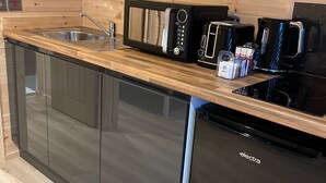 Cocina compacta con detalles de madera, electrodomésticos de acero inoxidable y lavavajillas integrado.