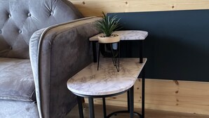 Una pequeña mesa redonda de metal negro con tapa de mármol y una planta en maceta.