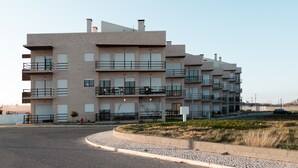 Een meerlaags woongebouw met balkons, een verharde oprit en een aangelegde tuin.