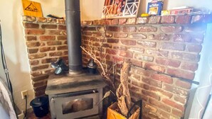 Une pièce rustique avec une cheminée en briques, un poêle à bois et une cheminée.