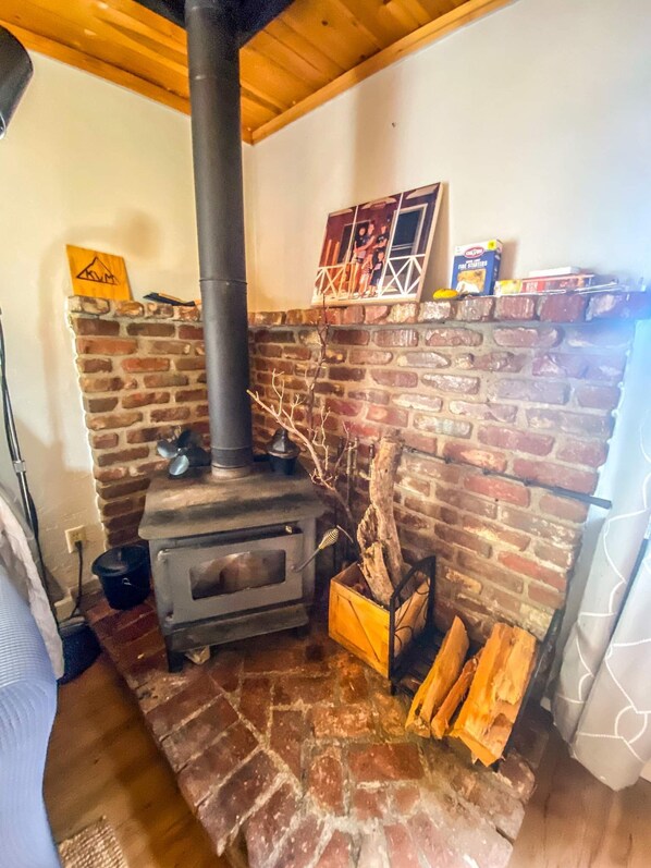 A rustic room with a brick fireplace, a wood-burning stove, and a chimney.