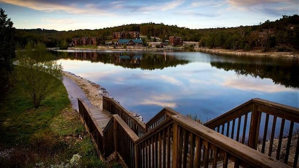 A wooden deck leading to a lake with a reflection of buildings and trees. - The LUX Stonebridge - No Stairs! Close to SDC! (Reeds Spring)