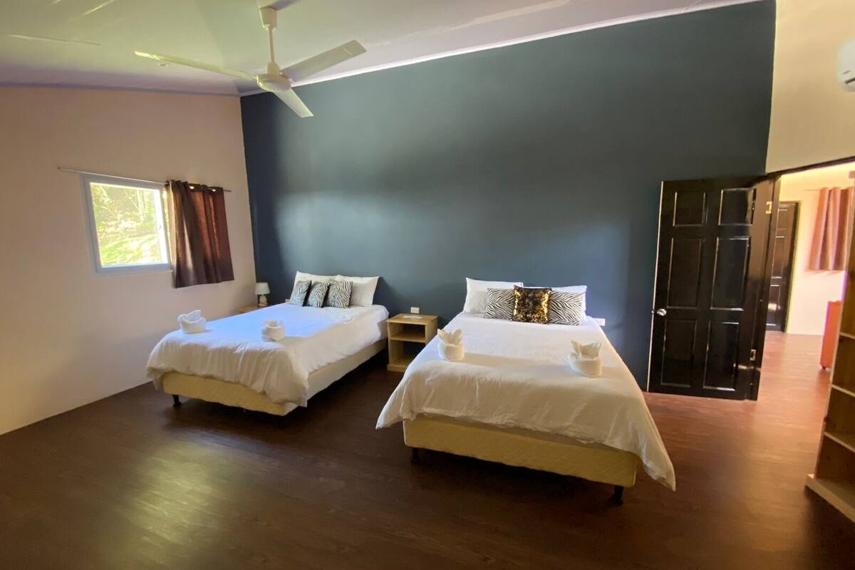 A hotel room with two beds, a ceiling fan, and a window with curtains.