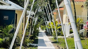 A pathway flanked by white bamboo structures leading to a building with a tiled roof. - Grand Park Manuel Antonio (Quepos)