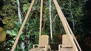 A night-time outdoor seating area with two chairs under a bamboo structure. - Grand Park Manuel Antonio (Quepos)
