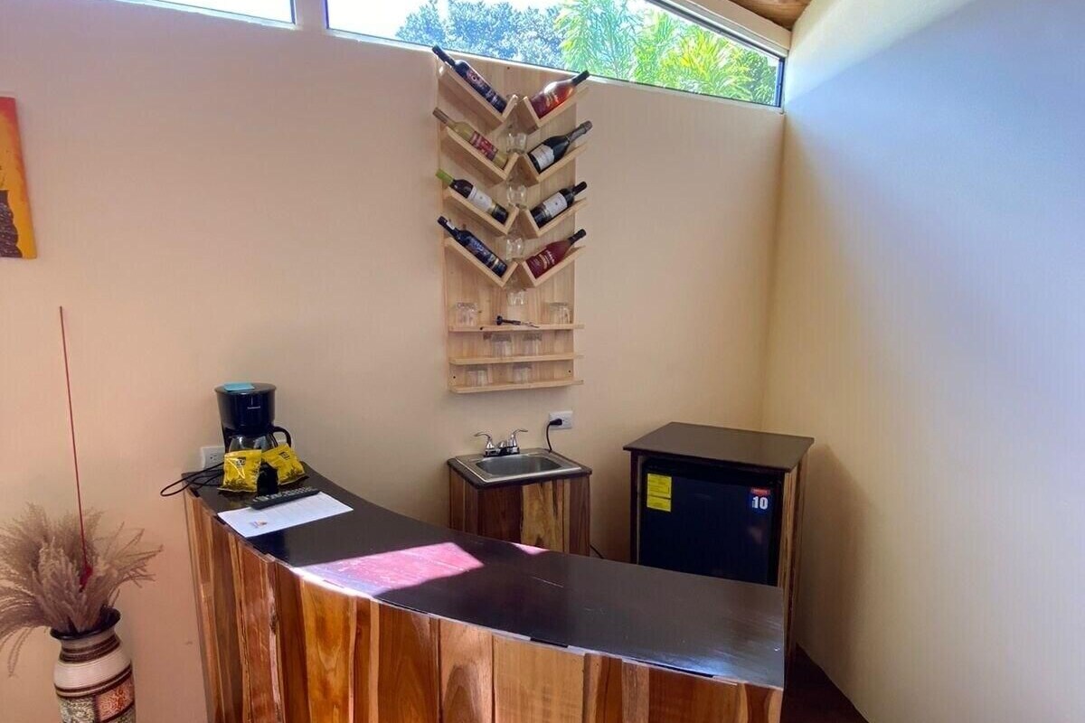 Una reception con piano in legno, una dispensa a muro per vini, un piccolo lavandino e un frigorifero.