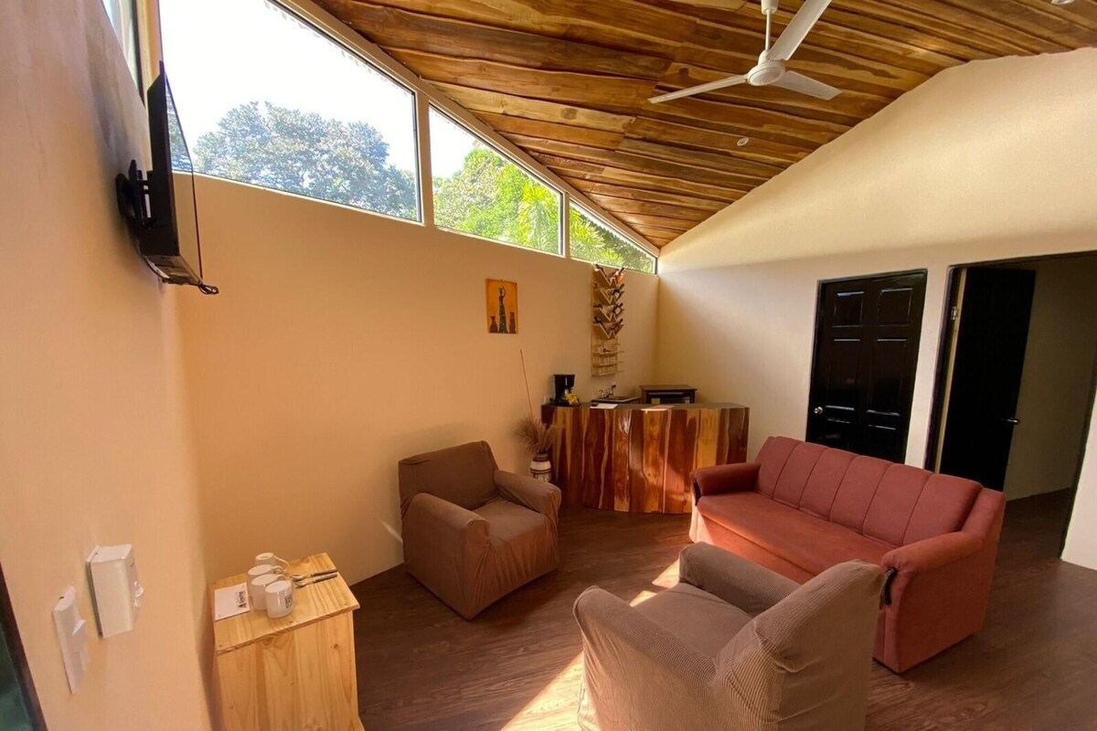 Una habitación amplia con techo de madera, un sofá rojo, un armario de madera y un mostrador de recepción.