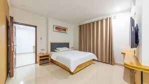 Een hotelkamer met een bed, nachtkastje, televisie en een deur die naar een andere kamer leidt.