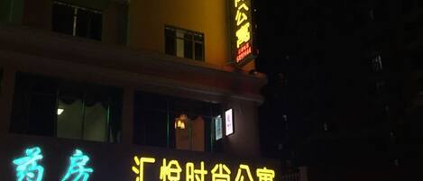 Un edificio con señalización iluminada que indica un hotel y un baño público.